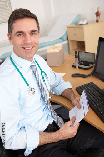 Photo: British male GP sitting at desk British male GP sitting at desk