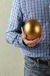 Cropped Studio Shot Of Man Holding Golden Egg