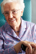 Senior Woman Relaxing In Chair Holding Walking Stick