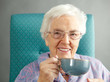 Senior Woman Relaxing In Chair With Hot Drink