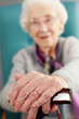 Senior Woman Relaxing In Chair Holding Walking Stick