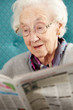 Senior Woman Relaxing In Chair Reading Newspaper