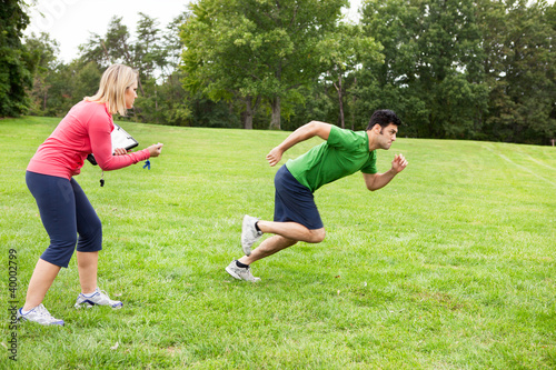 Photo: Fitness trainer timing runner in a field Fitness trainer timing runner in a field