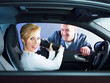 Customer in her car gets service book from master mechanic