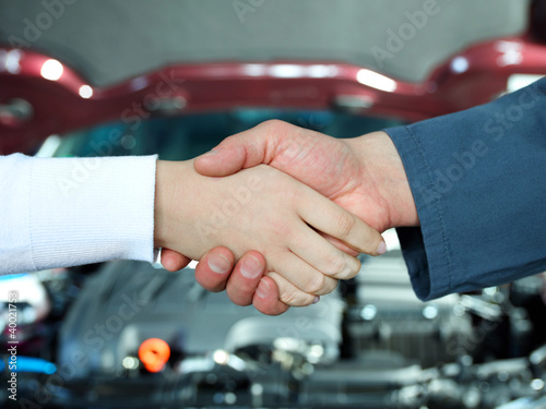 Foto: Female customer and master mechanic shaking hands in a garage Female customer and master mechanic shaking hands in a garage