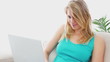 Blonde using a laptop on a sofa