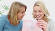 Woman opening a gift box with a friend