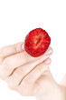 woman's hand showing a halved ( bitten ) fresh strawberry,
