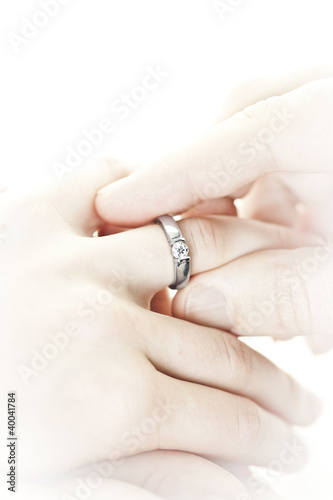 Photo: Man putting engagement ring on finger Man putting engagement ring on finger