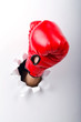 Hand in boxing glove through paper hole Hand in boxing glove through paper hole
