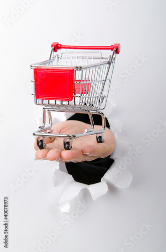Photo: Shopping cart through hole in paper Shopping cart through hole in paper
