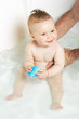 Cute baby held by father's hands while taking a bath