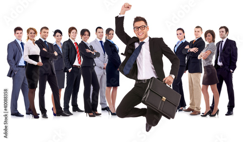 Photo: business man holding briefcase jumping in front of his team business man holding briefcase jumping in front of his team