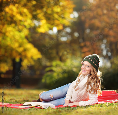Photo: Young smiling female reading a book in a park Young smiling female reading a book in a park