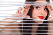 Woman peering through some blinds