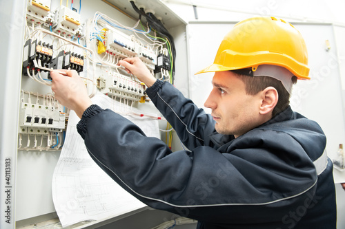 Foto: Electrician with drawing at power line box Electrician with drawing at power line box