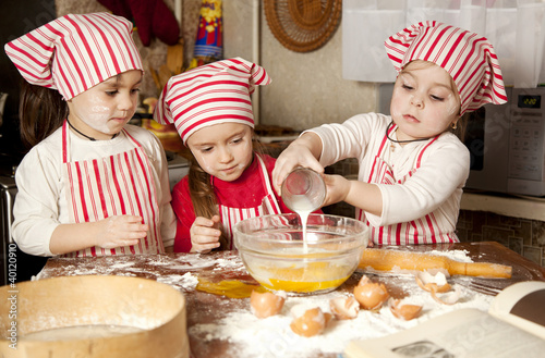 Photo: Three little chefs enjoying in the kitchen making big mess. Litt Three little chefs enjoying in the kitchen making big mess. Litt