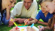 Happy family drawing together while lying on the grass
