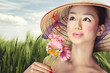 Beautiful vietnamese girl in a traditional hat is holding flower