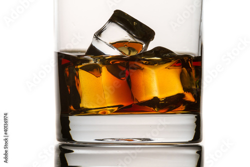 Photo: Closeup brandy with glass and ice cubes on white background Closeup brandy with glass and ice cubes on white background