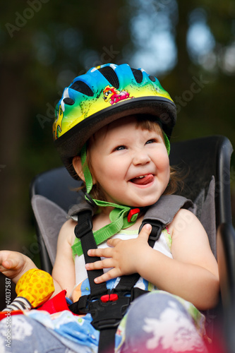Photo: Little girl in the seat bicycle with a helmet on his head Little girl in the seat bicycle with a helmet on his head