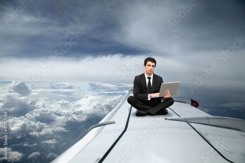 Photo: Businessman sat on the wing of an airplane Businessman sat on the wing of an airplane