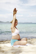 junge schwangere frau macht yoga am strand