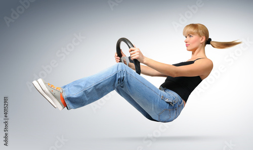 Photo: Young girl car driver with a wheel, concept Young girl car driver with a wheel, concept