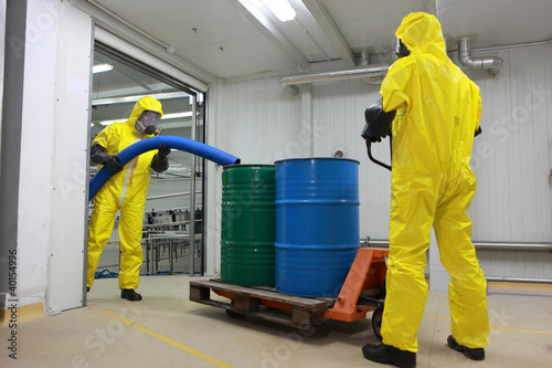 Photo: Two professionals working with toxic waste in factory Two professionals working with toxic waste in factory