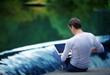 Man with laptop sitting over the waterfall