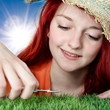 Foto: Girl with straw hat trims the synthetic turf with nail scissors Girl with straw hat trims the synthetic turf with nail scissors