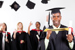 happy african graduate at graduation with classmates