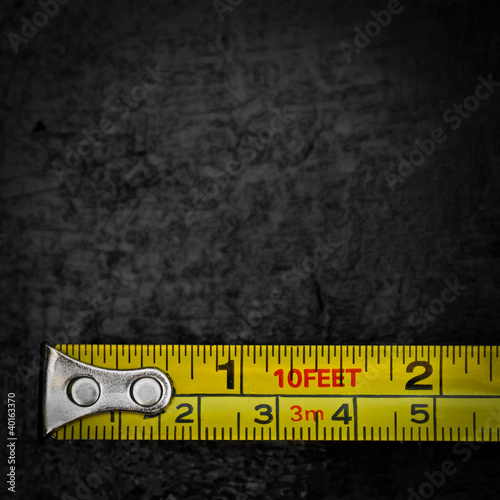 Photo: Measuring tape on a black metallic background Measuring tape on a black metallic background