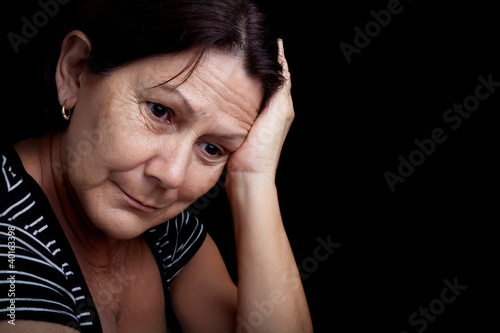 Photo: Older woman with a very sad expression isolated on black Older woman with a very sad expression isolated on black