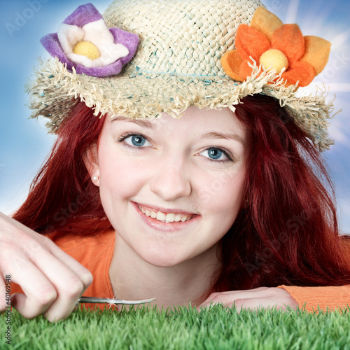 Foto: Teenager with flower hat cuts grass with nail scissor Teenager with flower hat cuts grass with nail scissor