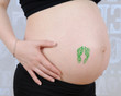 Photo: closeup of pregnant belly with baby feet stamp closeup of pregnant belly with baby feet stamp