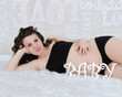 beautiful pregnant woman laying with baby spelled in letters