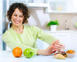 Beautiful Young Woman choosing between Fruits and Sweets