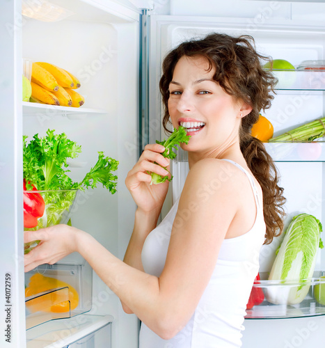 Photo: Beautiful Young Woman near the Refrigerator with healthy food Beautiful Young Woman near the Refrigerator with healthy food
