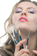 blonde with a bunch of makeup tools holding lifted up isolated o