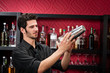 Young bartender make cocktail shaking drinks