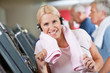 Seniorin mit Kopfhörern im Fitnesscenter