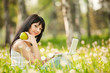 Cute woman with white laptop in the park with dandelions