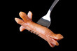 Hot wiener on the fork, isolated on black