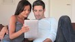Couple sitting in sofa with electronic tablet