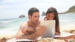 Couple at the beach using electronic tablet
