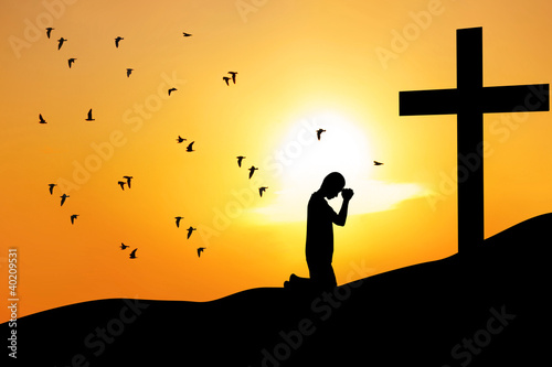 Photo: Christian background: man praying under the cross Christian background: man praying under the cross