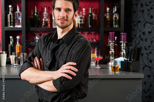 Photo: Barman in black standing at cocktail bar Barman in black standing at cocktail bar