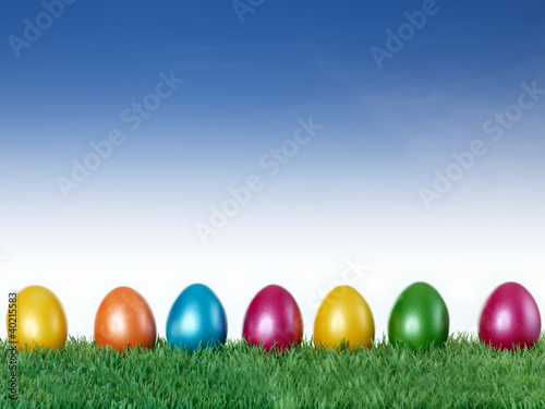Photo: Happy Easter! Colourful eggs in the meadow with blue sky Happy Easter! Colourful eggs in the meadow with blue sky