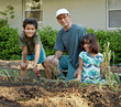 Grandfather and Children Planting in Community Garden